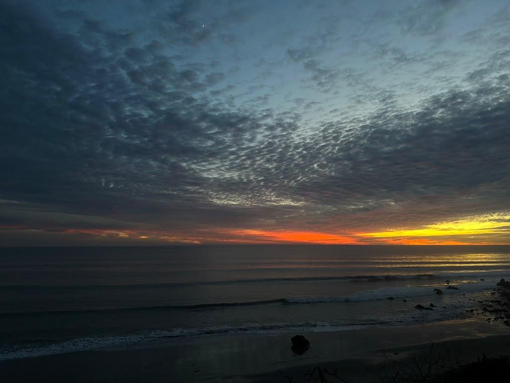 Orange sunset beneath textured clouds above the Malibu coast