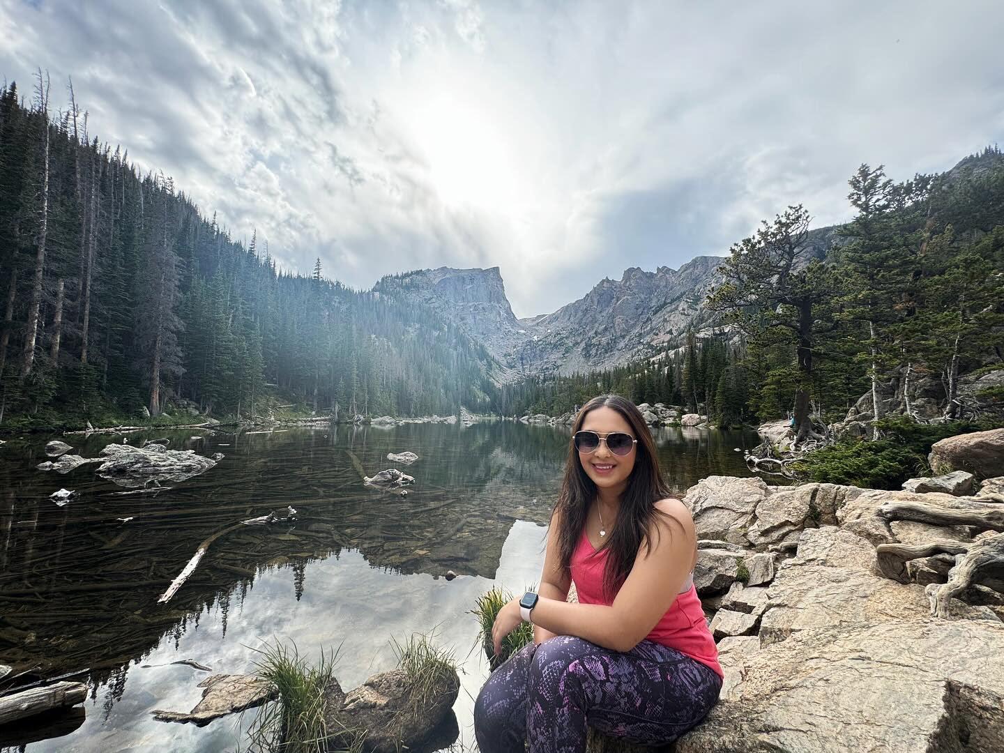 Traveller resting beside a clear mountain lake on a rocky shoreline