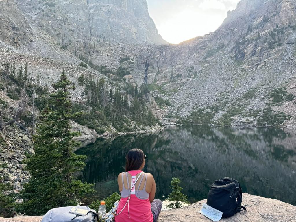 Traveller seated above a deep alpine lake surrounded by rugged mountains