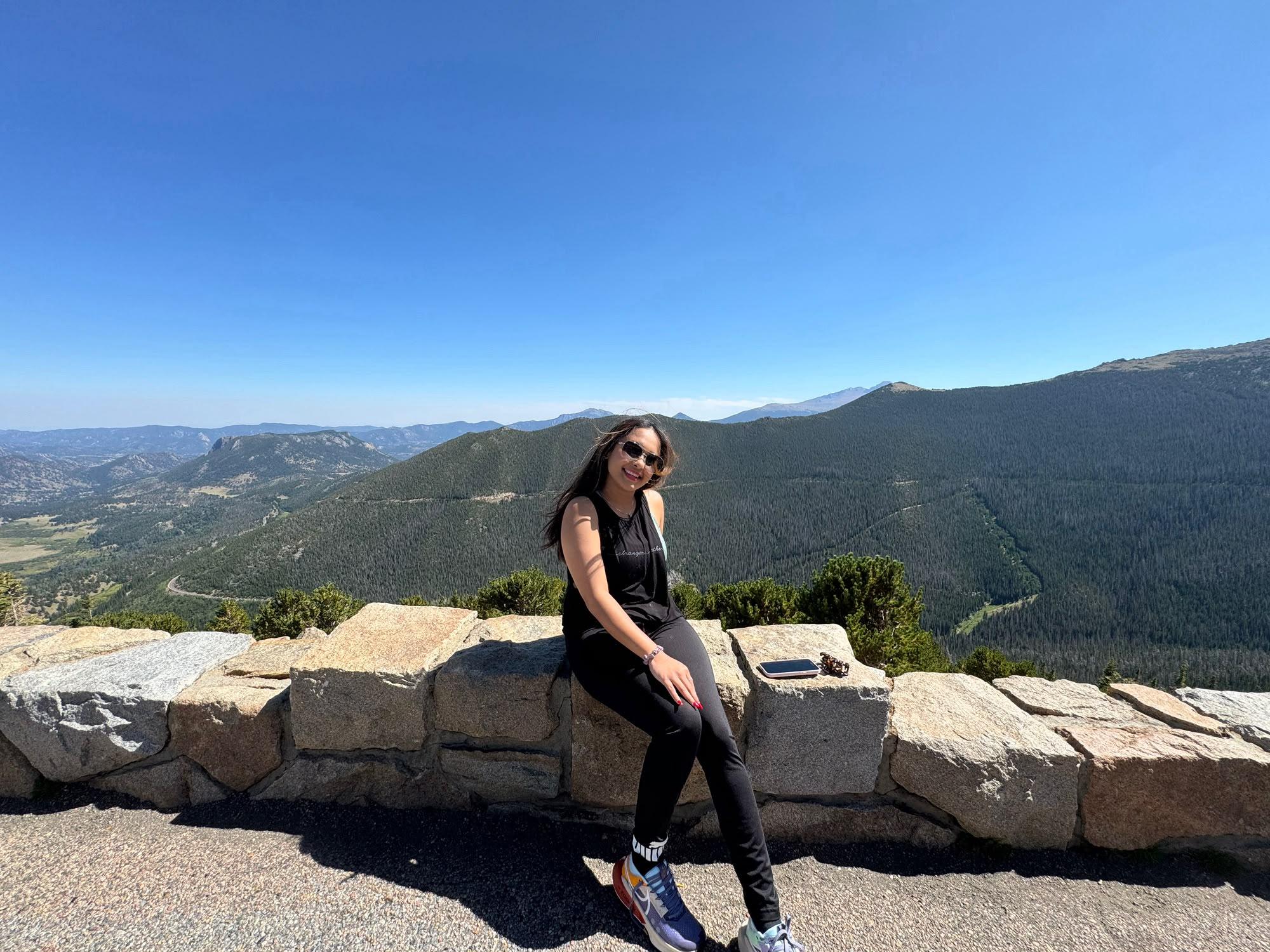 Traveller posing above the Estes Park valley with layered Colorado mountains behind