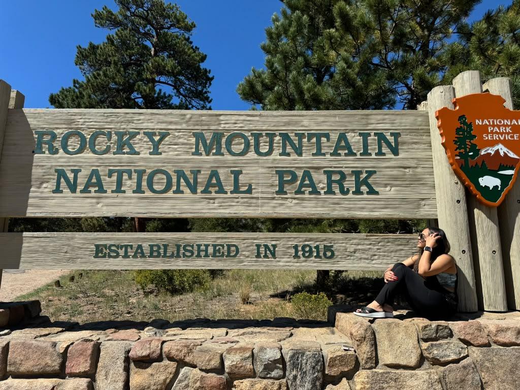 Traveller beside the Rocky Mountain National Park entrance sign