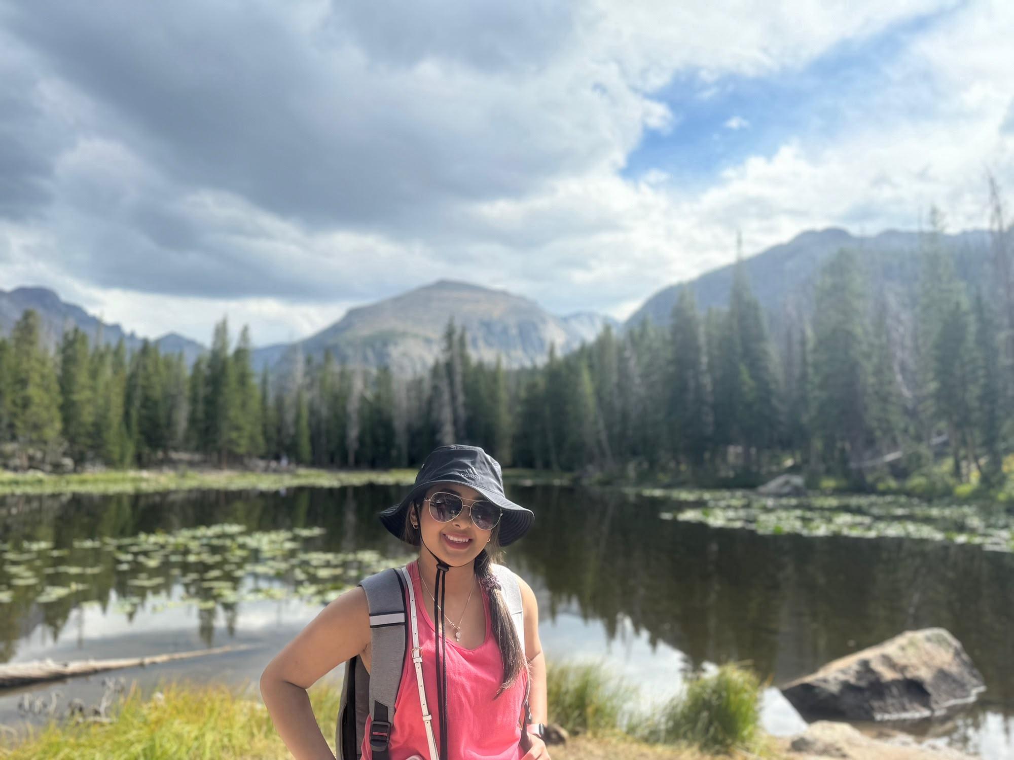 Traveller beside a calm alpine lake surrounded by pine trees