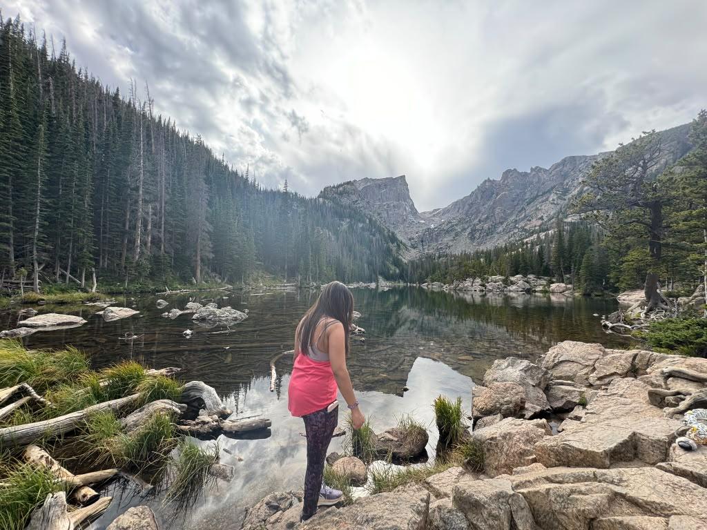 Traveller standing beside a rocky alpine lake beneath steep mountain walls
