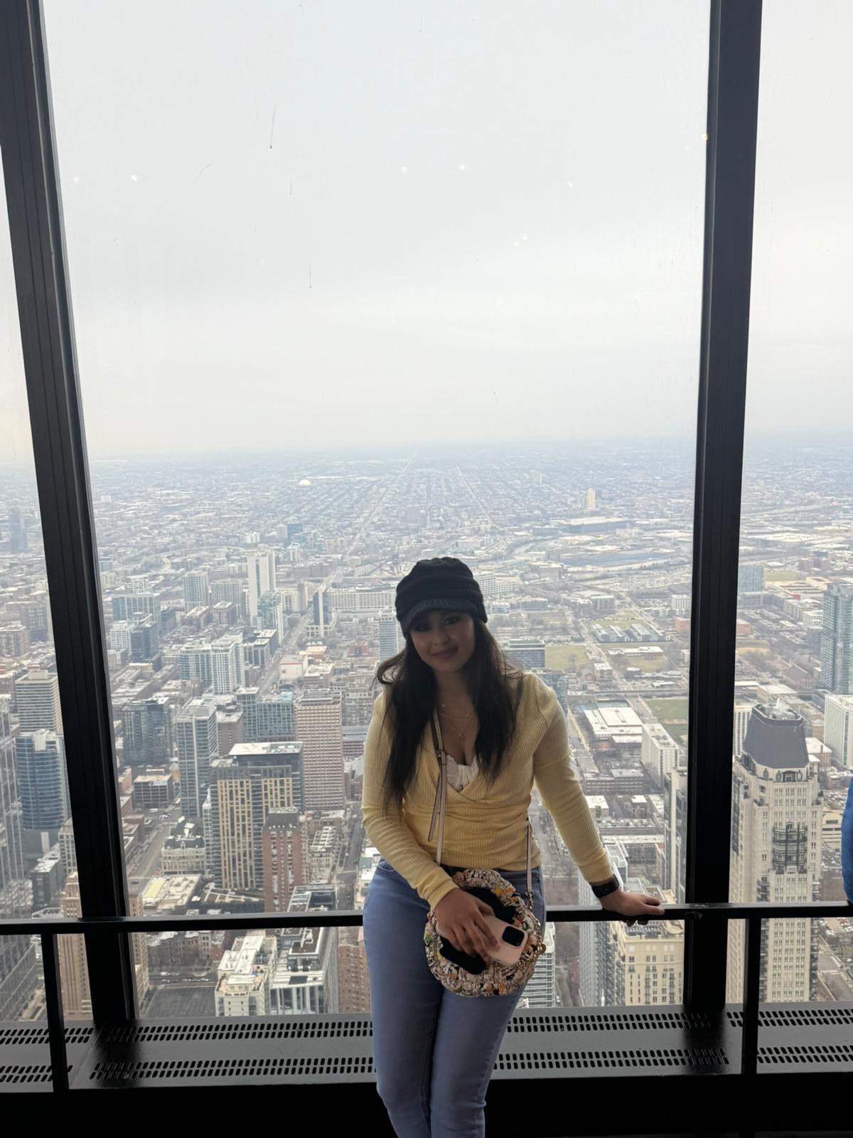 Traveller posing beside a panoramic Chicago observation-deck window