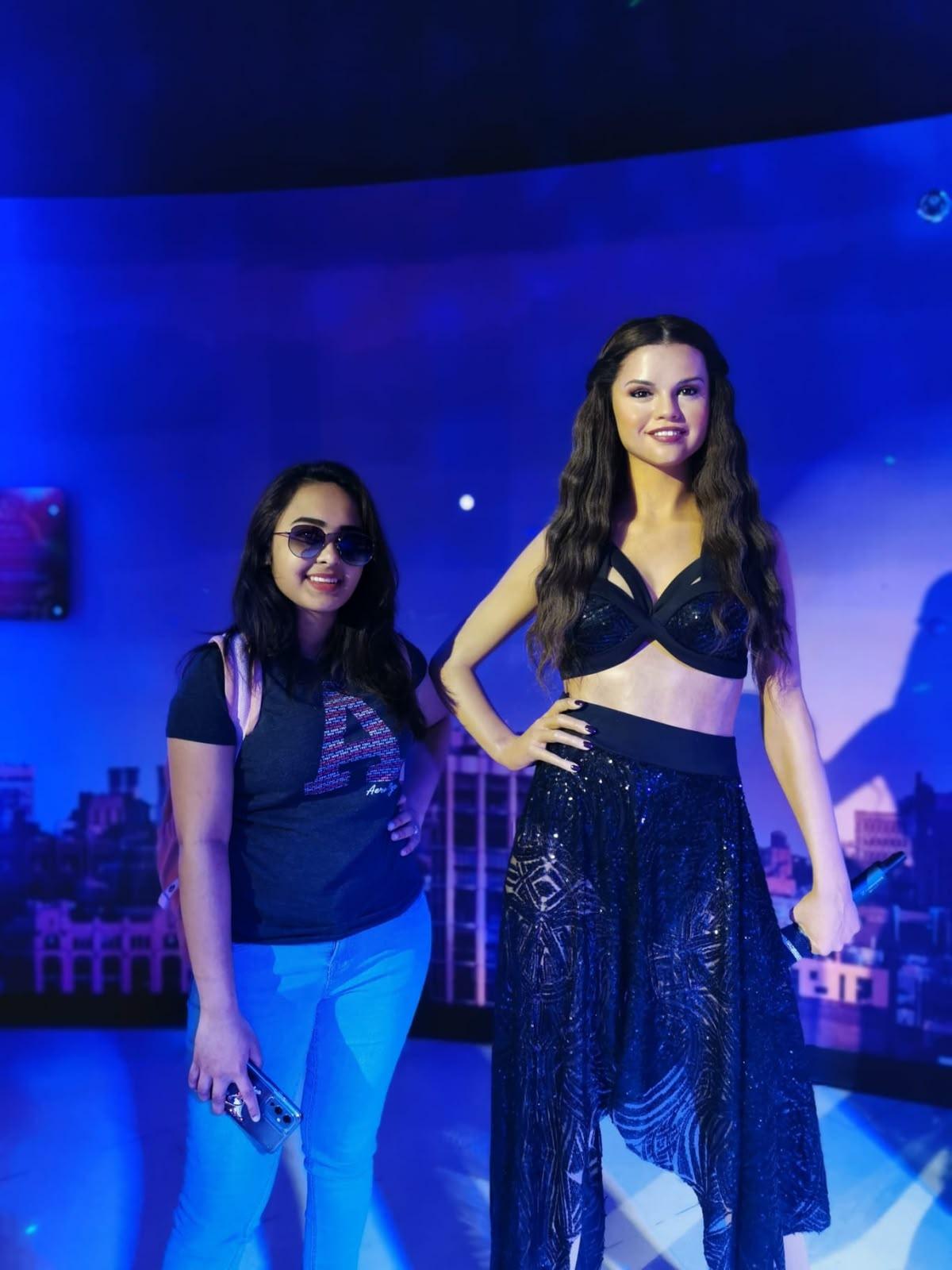 Personal portrait beside a music-themed wax display under blue lighting