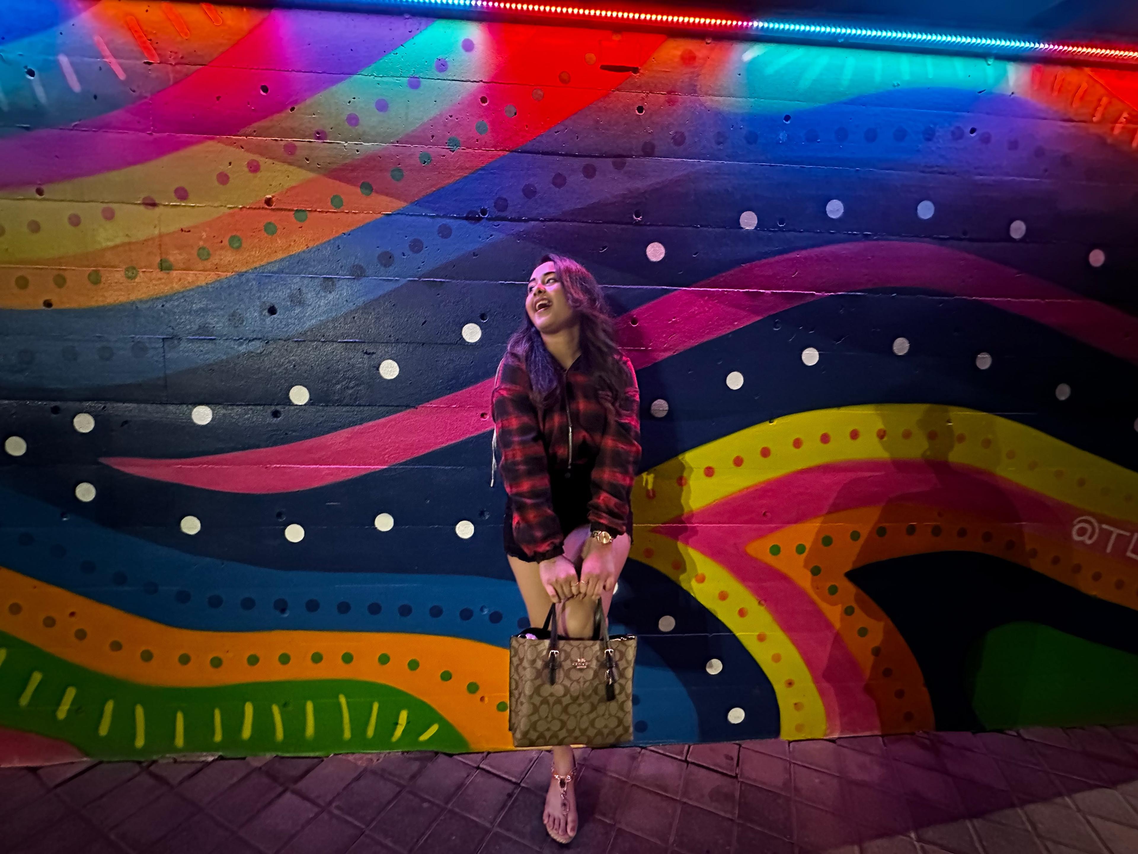 Traveller laughing in front of a colorful Oklahoma City mural