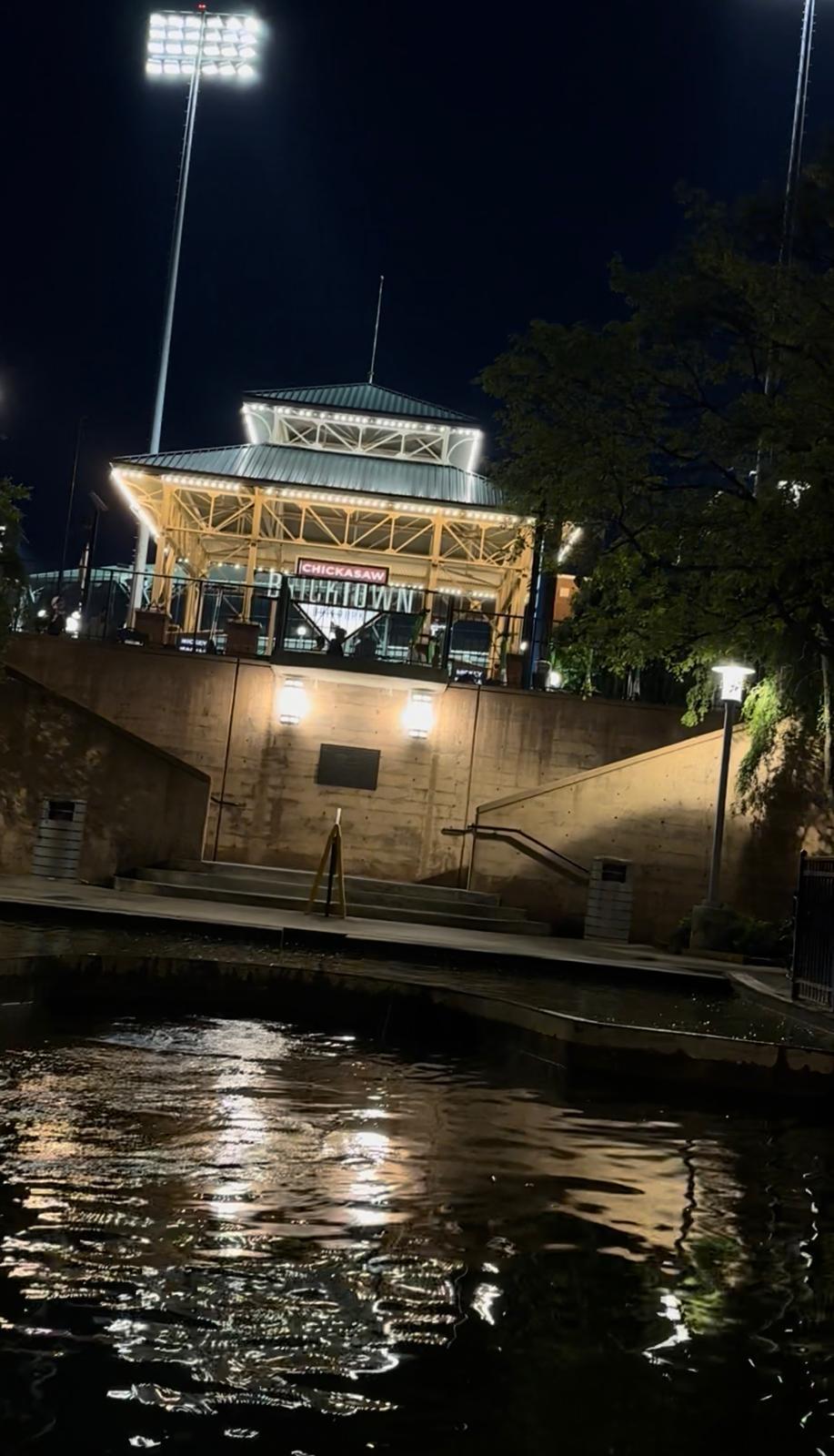 Chickasaw Bricktown Ballpark illuminated beside the canal at night