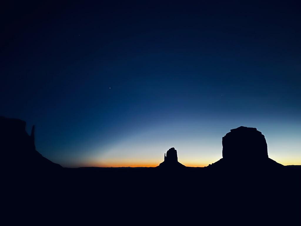 Monument Valley formations silhouetted along the pre-dawn horizon
