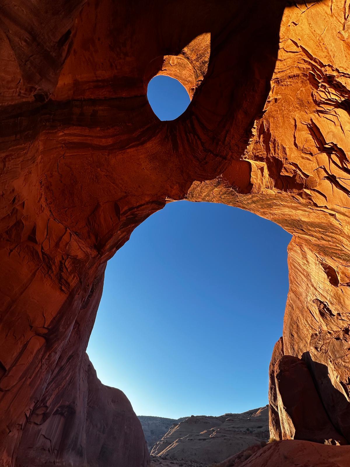 View through multiple natural sandstone openings toward blue sky
