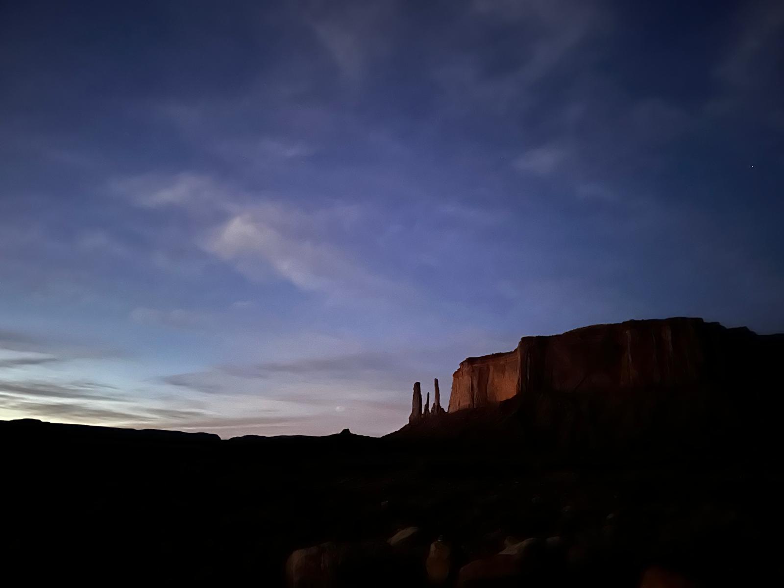 Blue-hour Monument Valley horizon with dark sandstone silhouettes