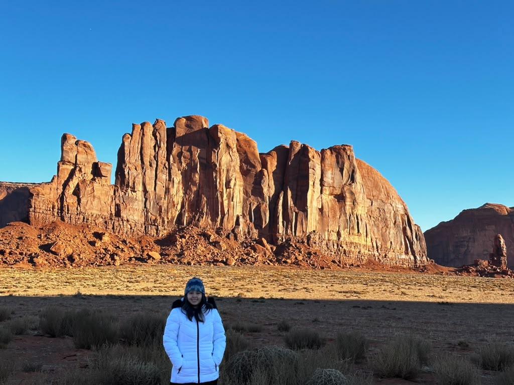 Traveller standing before sunlit Monument Valley sandstone formations