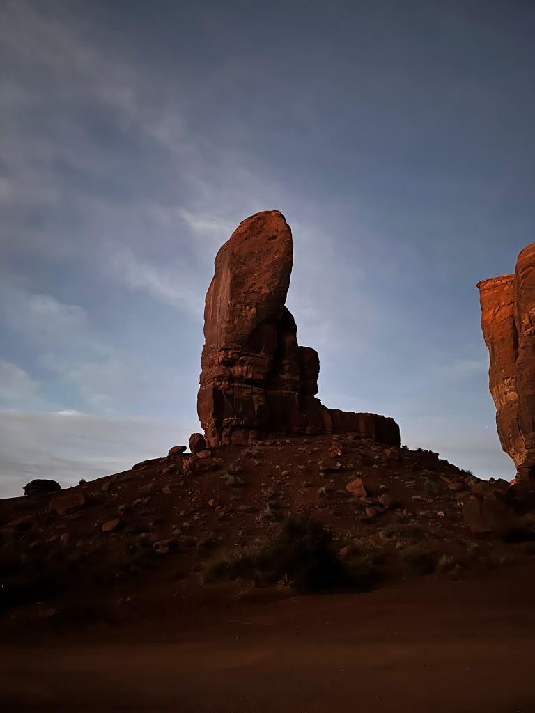 Tall Monument Valley rock spire silhouetted against a darkening sky