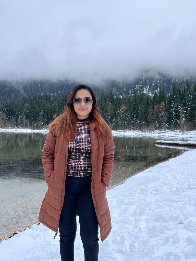 Traveller standing beside snowy water and forested mountains
