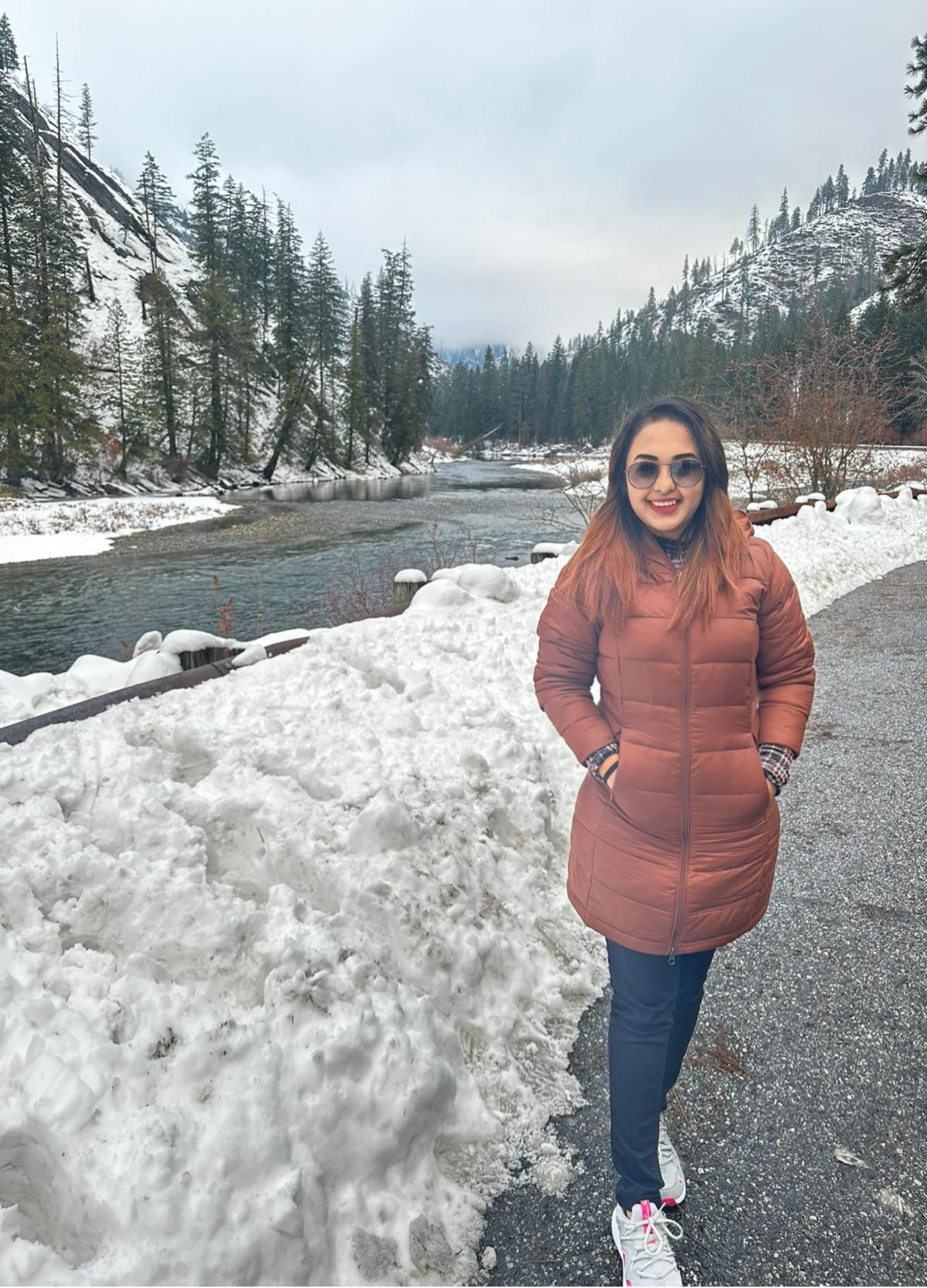 Traveller beside a snowy river in a forested mountain valley