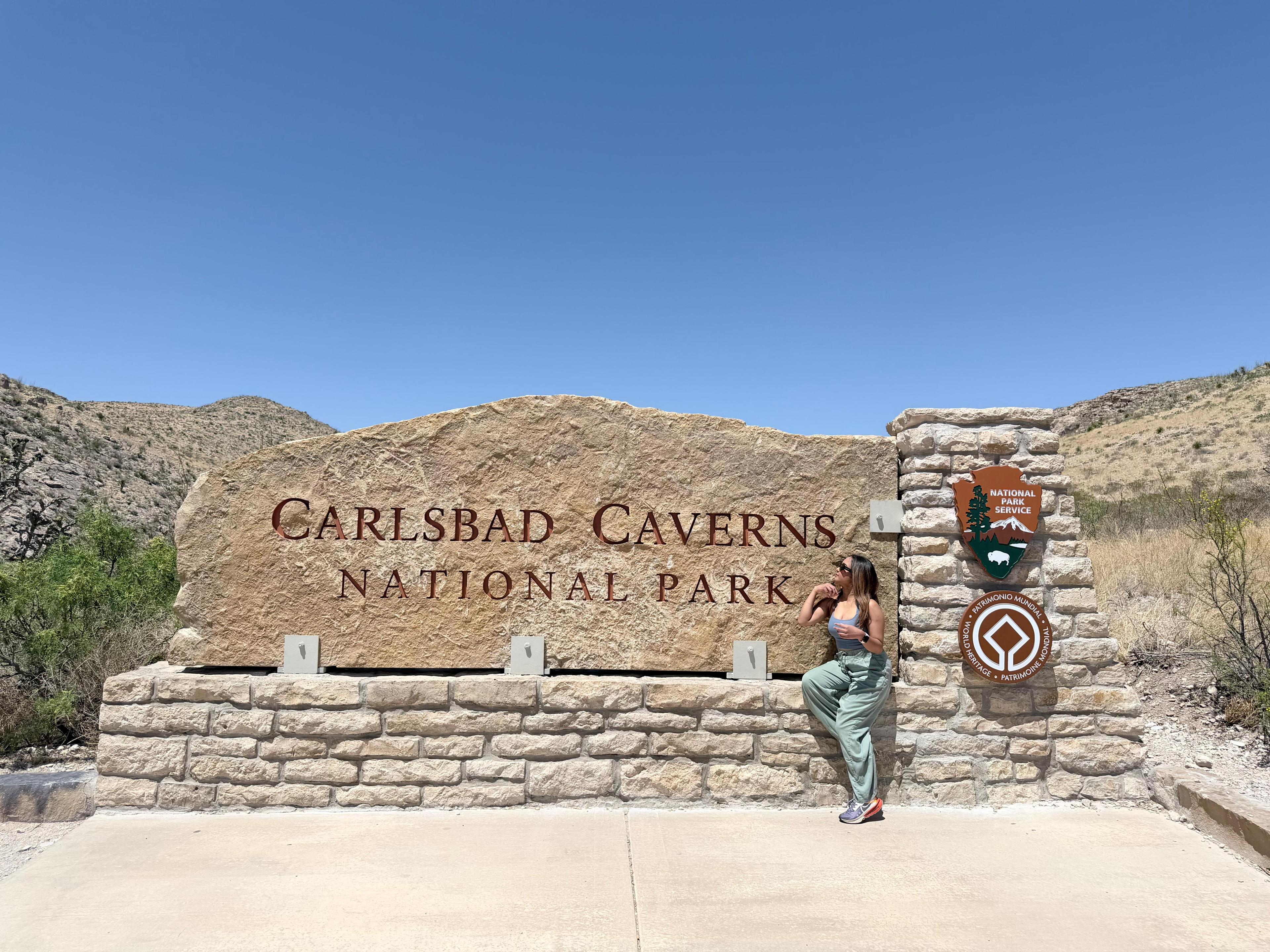 Traveller beside the Carlsbad Caverns National Park entrance sign