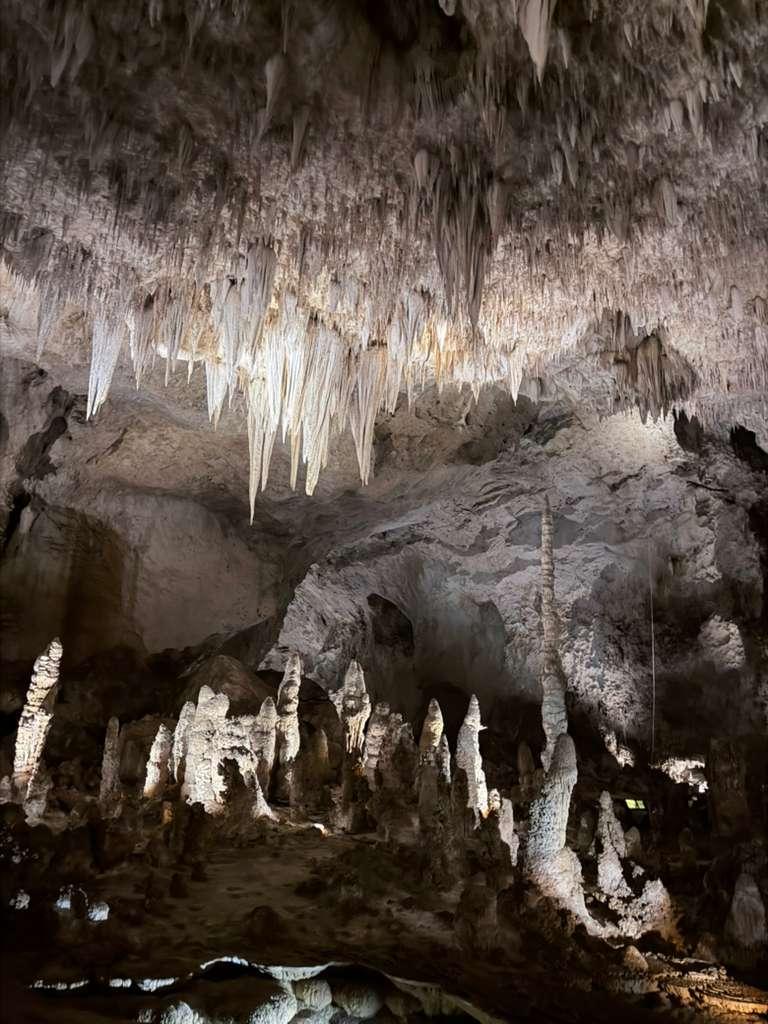 Stalactites and stalagmites inside a softly lit cavern room